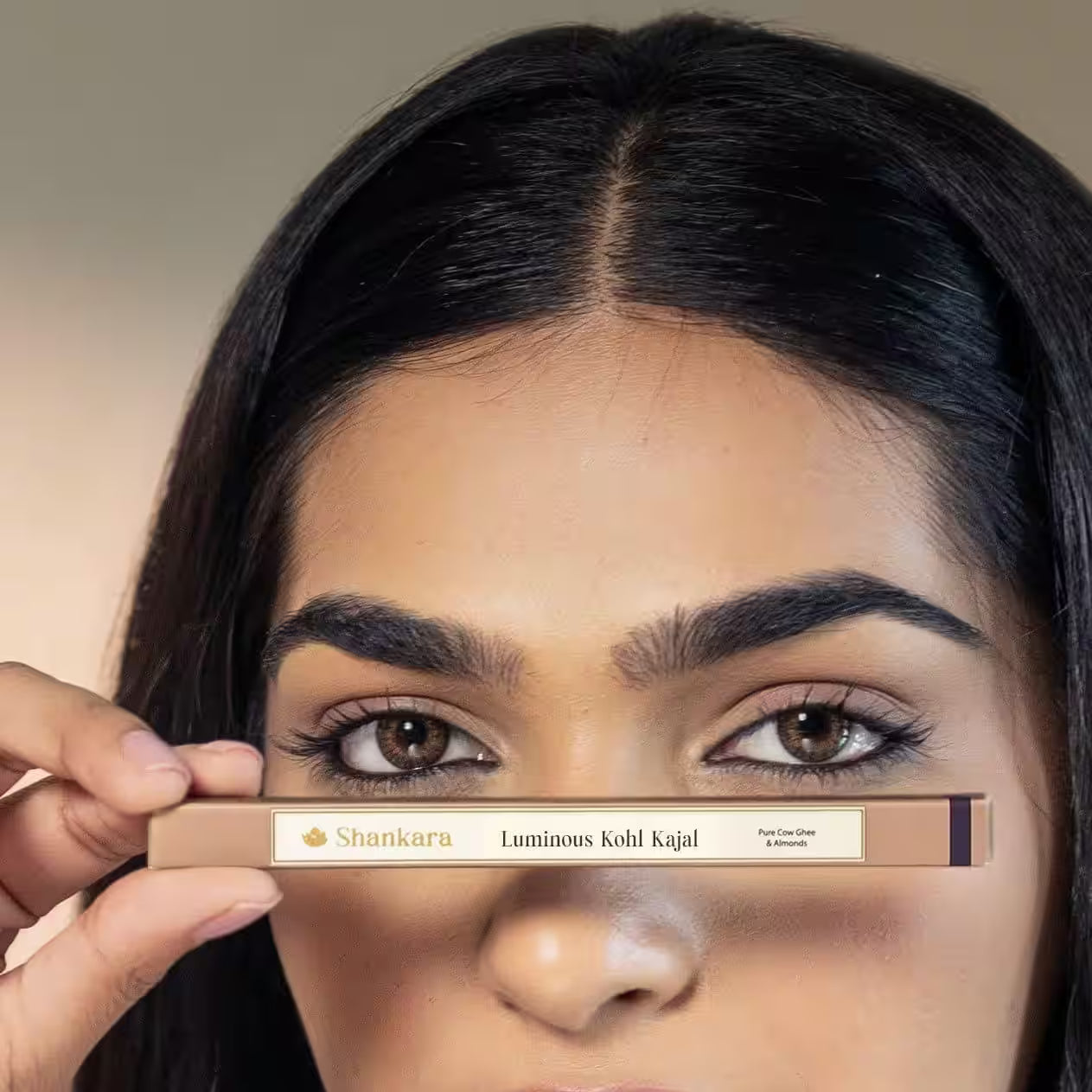 Woman holding a Shankara Luminous Kohl Kajal product in front of her eyes.
